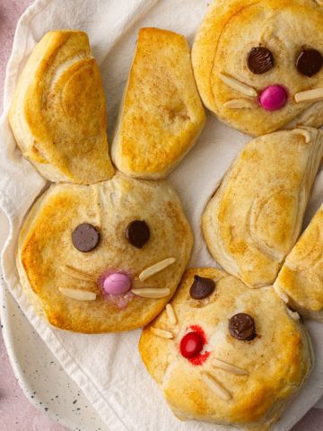 Close-up of baked Easter Bunny Biscuits on a plate with almond whiskers and candy faces.