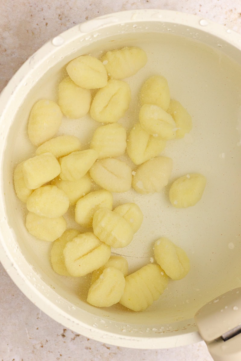 Gnocchi boiling in a pot of salted water just before they float to the top.