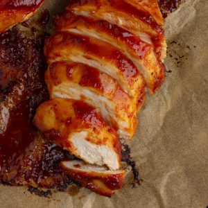 Close-up of juicy, sliced BBQ chicken breast with sticky sauce and golden edges.