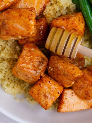 Close-up of hot honey salmon bites served over couscous with green beans.