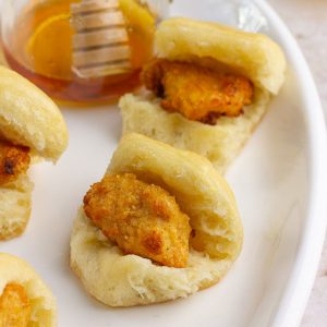 Finished copycat chicken minis served on a platter with a jar of honey in the background.