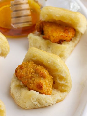 Finished copycat chicken minis served on a platter with a jar of honey in the background.
