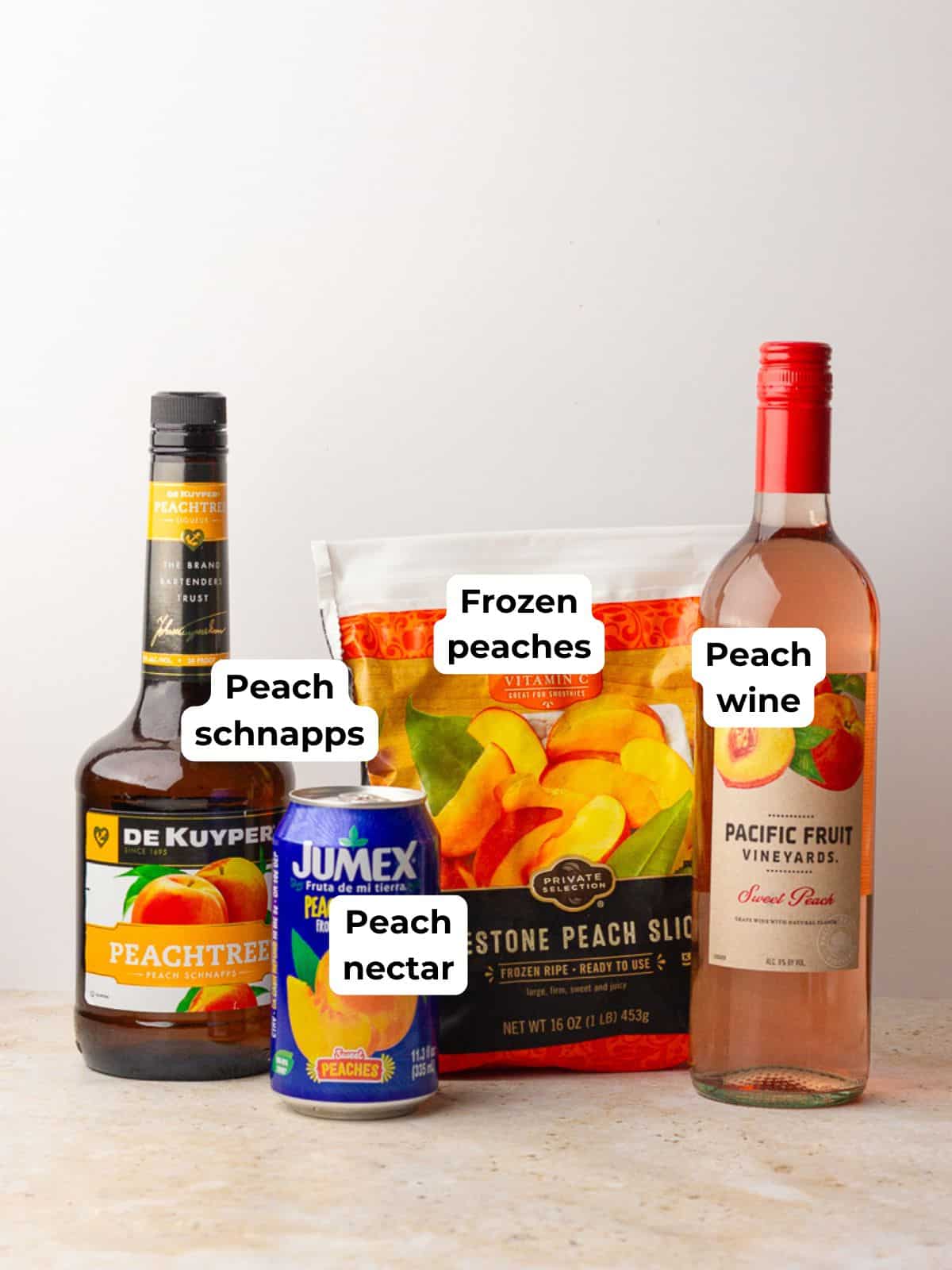 Labeled ingredients for peach sangria including peach schnapps, peach nectar, frozen peaches, and peach wine.