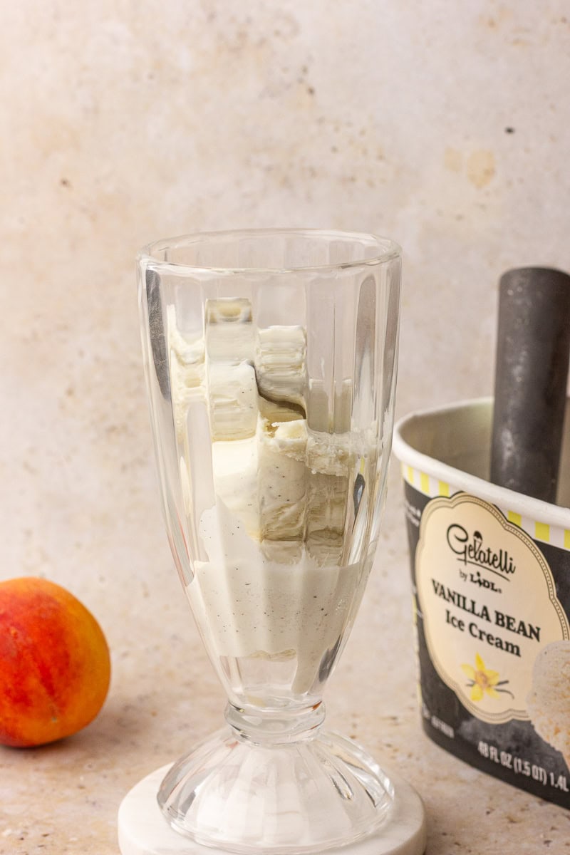 A glass with two scoops of vanilla ice cream, ready for the kombucha to be poured over.