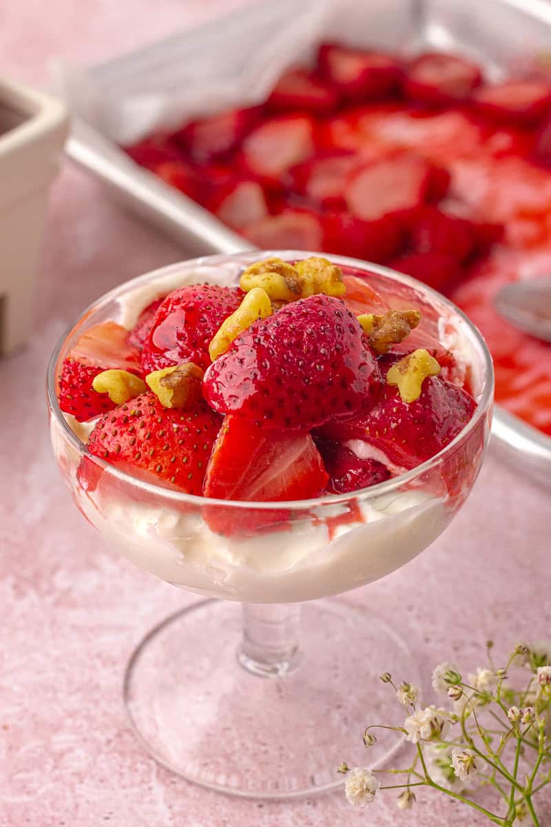 Roasted strawberries are layered over creamy yogurt in a glass dessert dish.