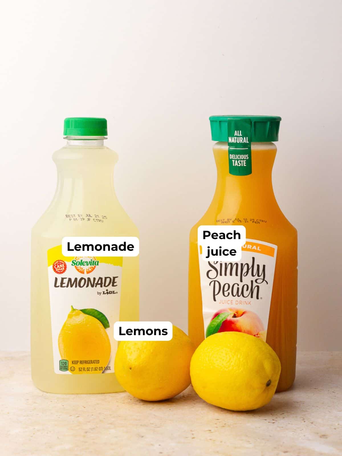 Ingredients for southern peach lemonade including lemonade, Simply Peach juice, and fresh lemons on a counter.