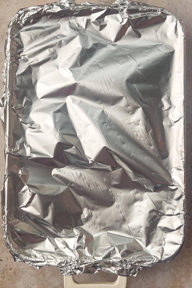 Casserole dish covered tightly with foil before baking the Boursin chicken orzo.
