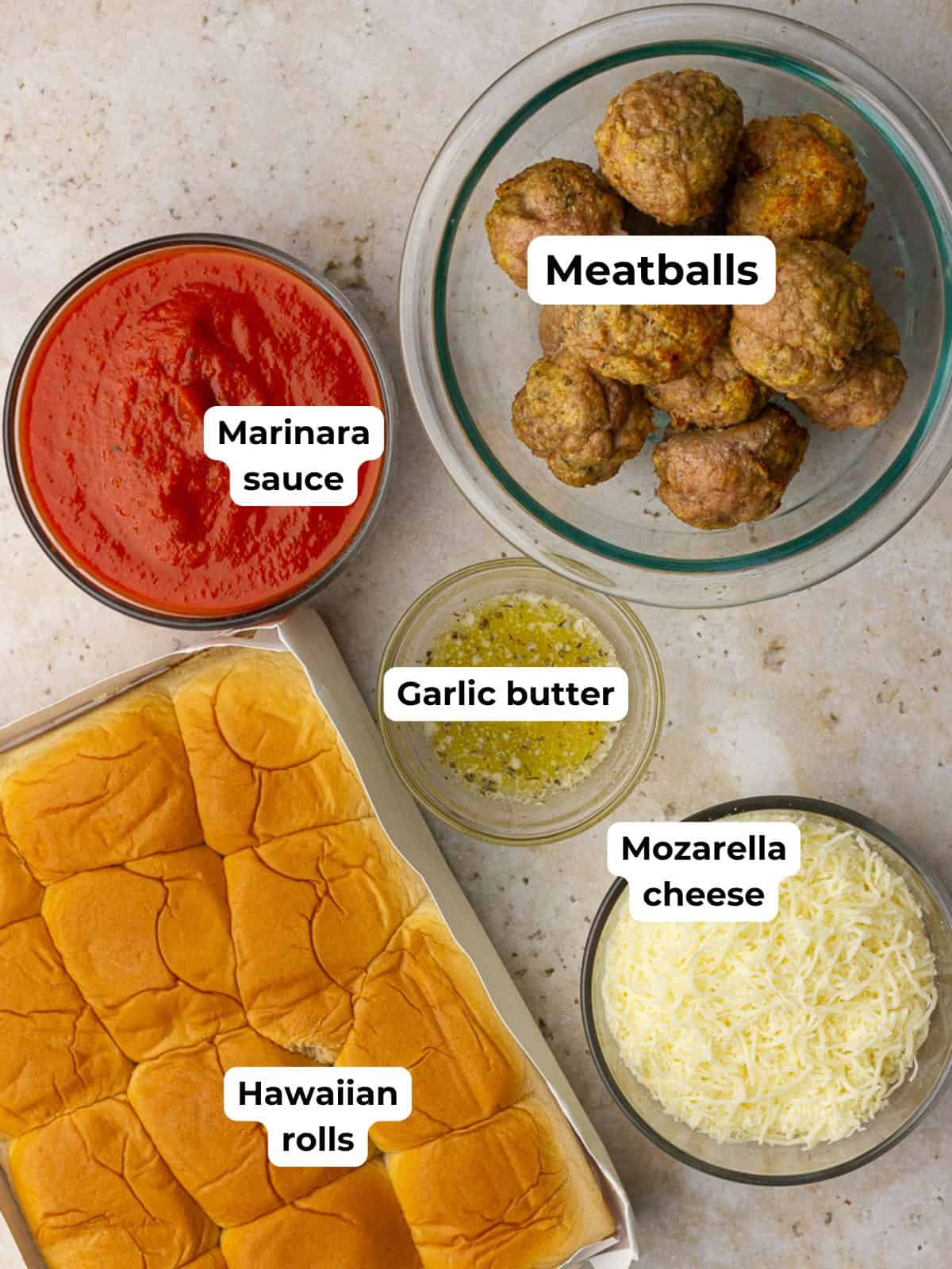 All the ingredients laid out to make Hawaiian roll meatball sliders, including rolls, cheese, sauce, and meatballs.
