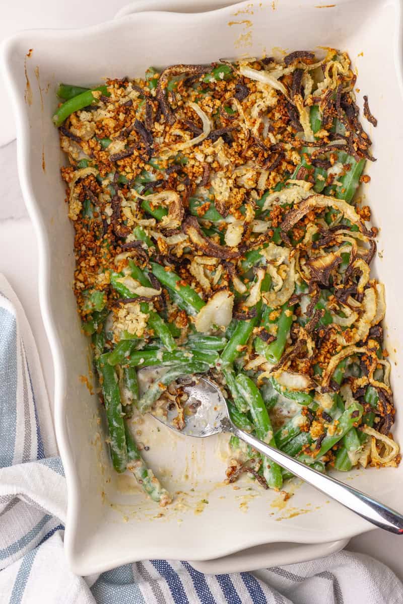 Overhead view of a baked green bean casserole with crispy onions in a white baking dish.
