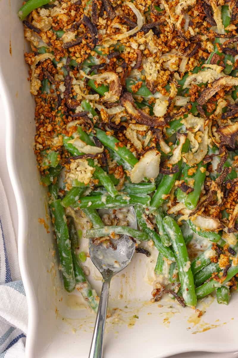 Partially eaten green bean casserole showing creamy interior and crispy onion topping.