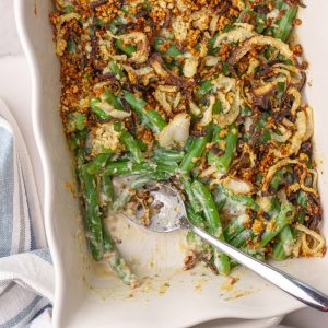 Close-up of green bean casserole with golden brown onions and creamy filling in a white dish.