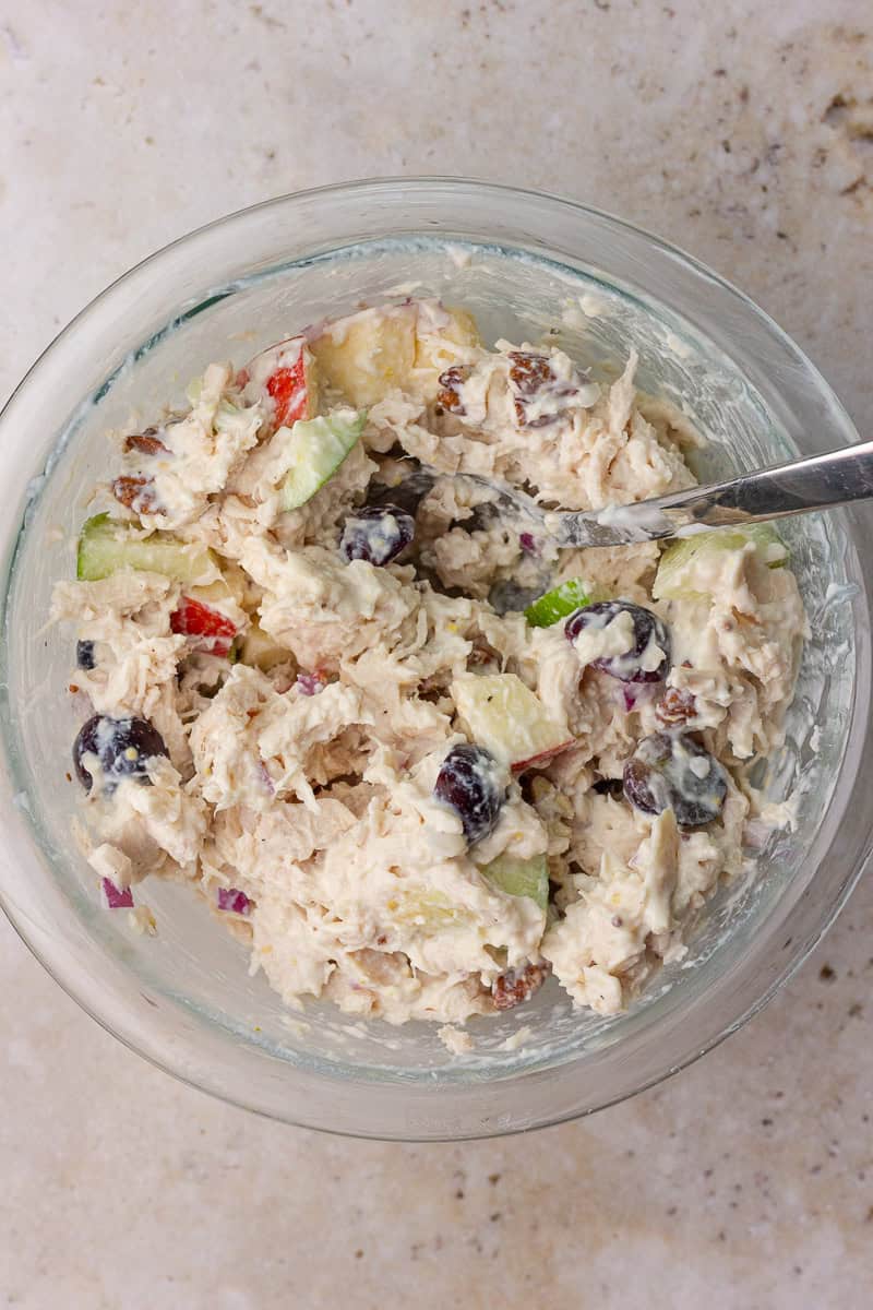 Overhead view of the mixed Waldorf chicken salad in a glass bowl, ready to serve.