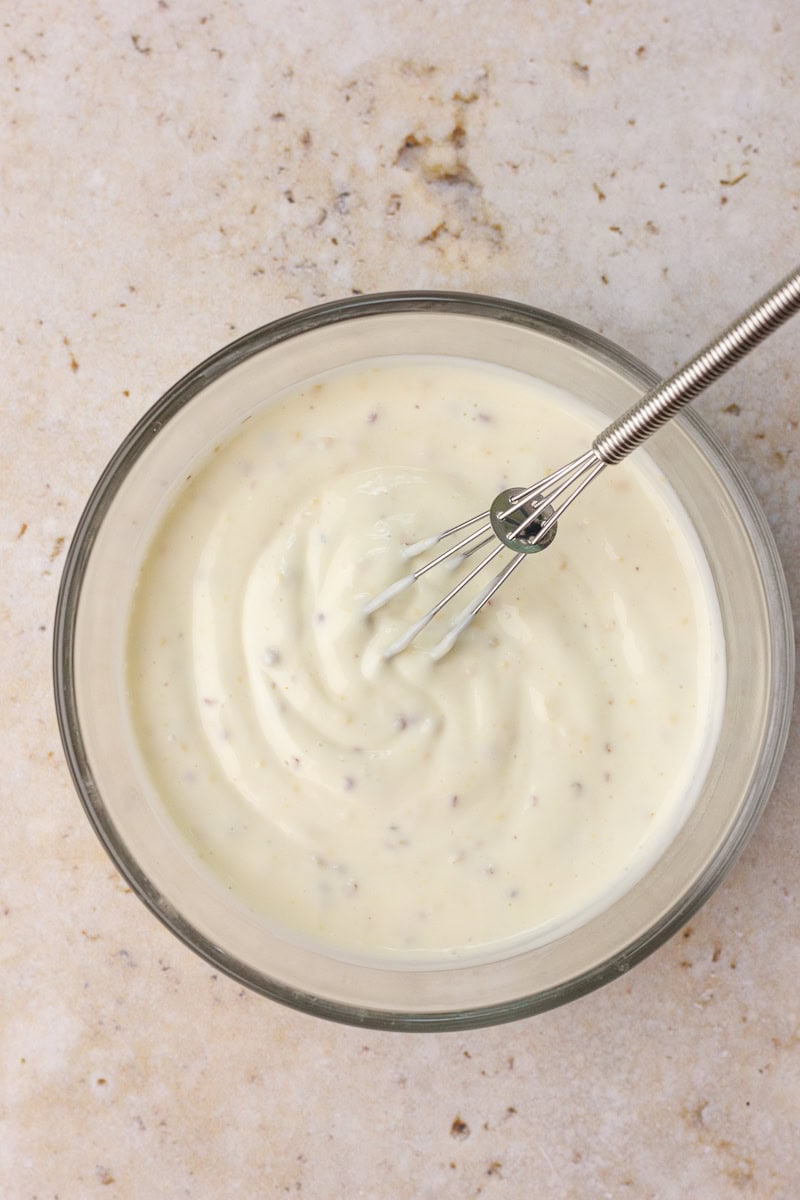 Small bowl of creamy Greek yogurt dressing whisked and ready to pour over salad ingredients.