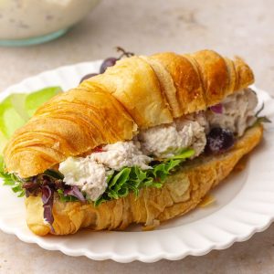 Waldorf chicken salad croissant sandwich plated with fresh greens and apple slices, styled for a blog hero image.