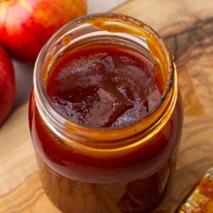 Close-up of homemade Apple BBQ Sauce in a small glass jar with a golden, smooth texture.