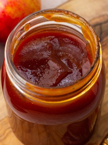 Close-up of homemade Apple BBQ Sauce in a small glass jar with a golden, smooth texture.