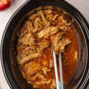 Image showing tender apple pulled pork in a black crockpot.