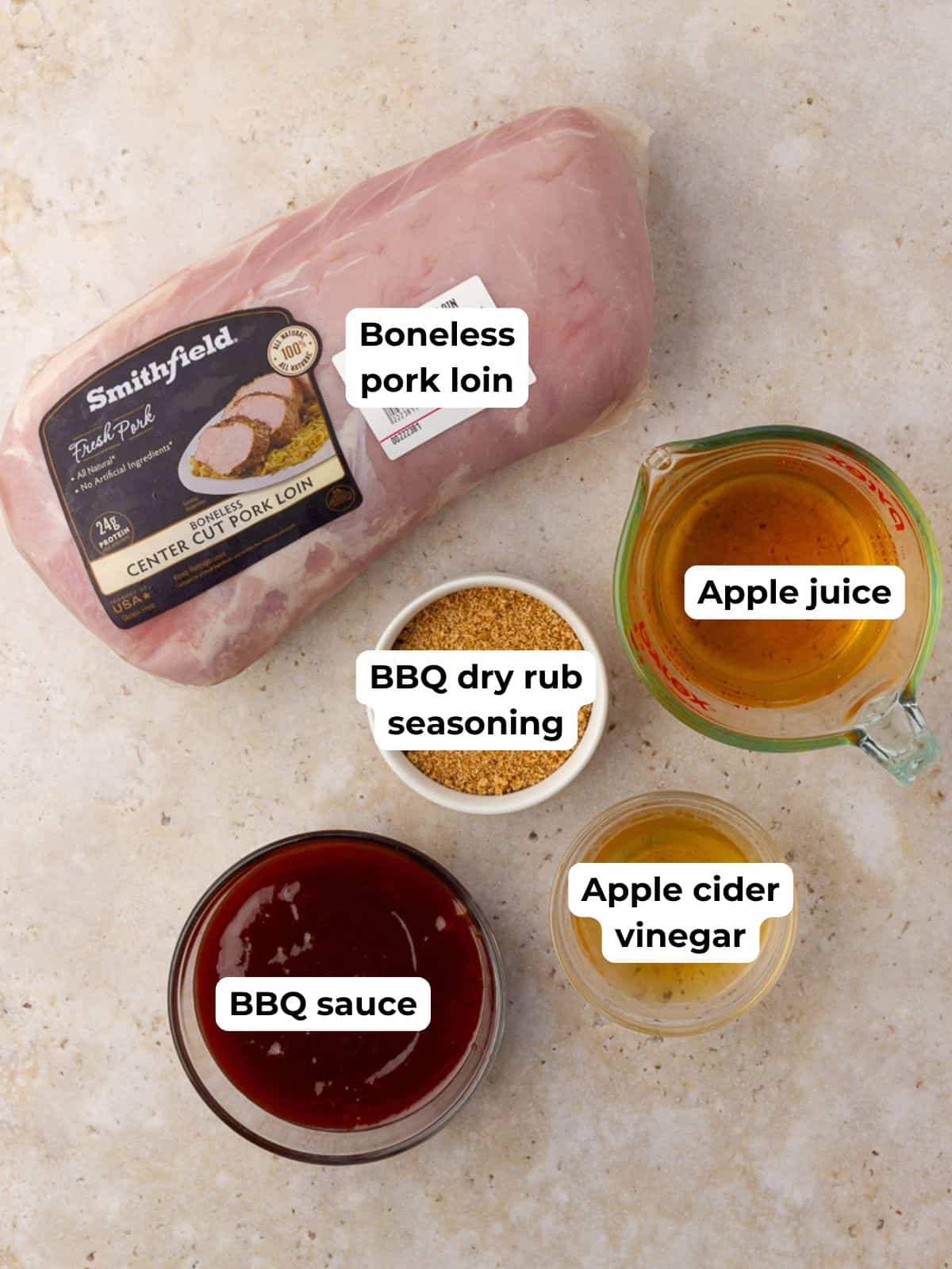 Overhead shot of labeled ingredients for apple pulled pork, including pork loin, apple juice, BBQ sauce, vinegar, and dry rub.