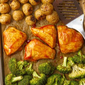 Overhead view of BBQ chicken sheet pan dinner with golden potatoes and broccoli, ready to serve.