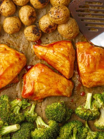 Overhead view of BBQ chicken sheet pan dinner with golden potatoes and broccoli, ready to serve.