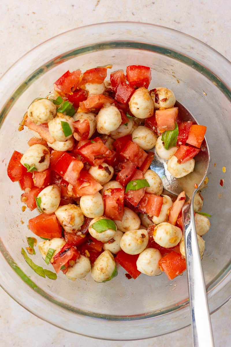 The tomato and mozzarella mixture fully combined in a glass bowl, ready to be spooned onto toasted bread.