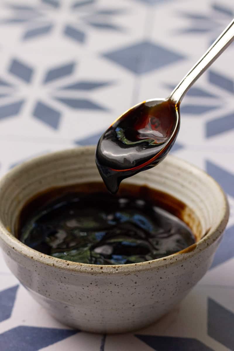 A spoonful of thick, glossy fig balsamic glaze being lifted from a bowl.