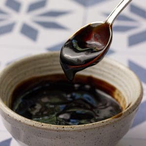 Close-up of fig balsamic glaze dripping off a spoon over a bowl.