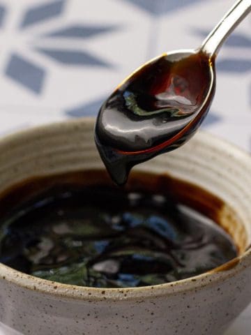 Close-up of fig balsamic glaze dripping off a spoon over a bowl.