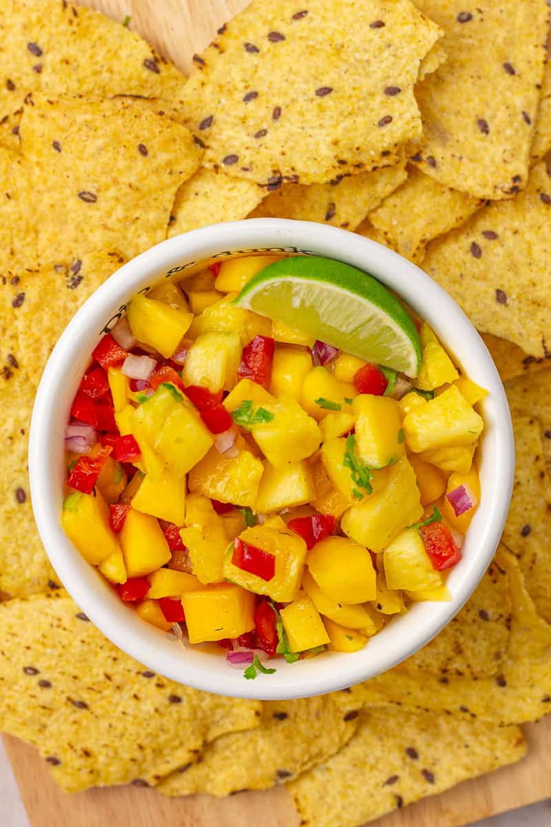 Overhead view of a white bowl filled with pineapple mango habanero salsa and a lime wedge.