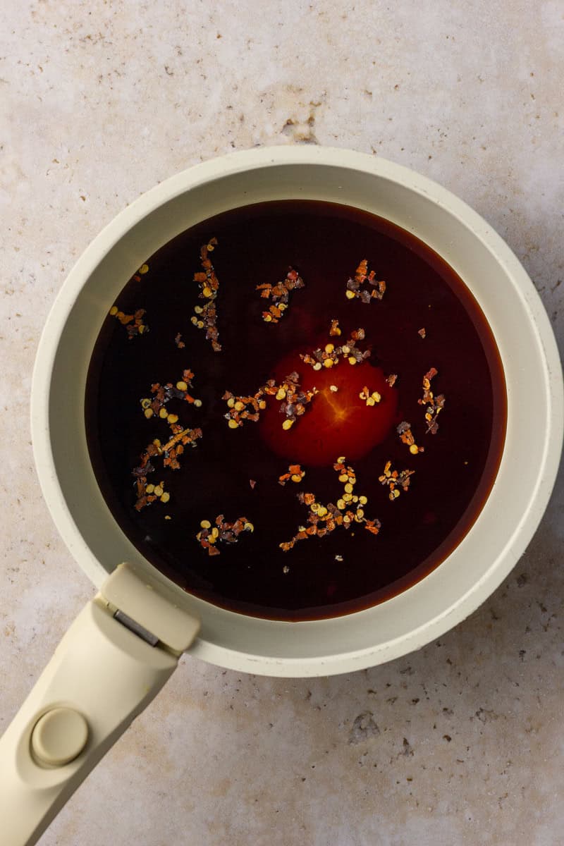 Balsamic vinegar, honey, and red pepper flakes are combined in a saucepan before simmering.