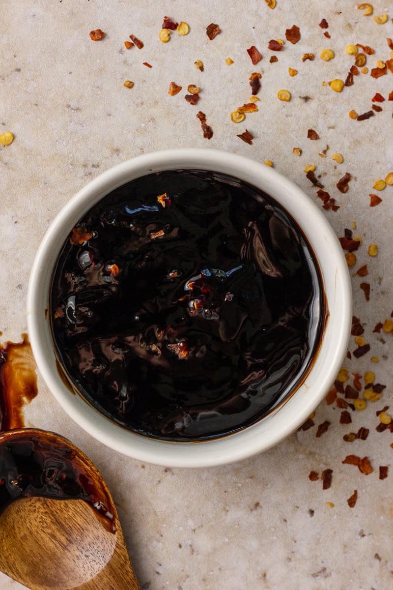 The thick spicy balsamic glaze is served in a small bowl with flakes of chili scattered on top.