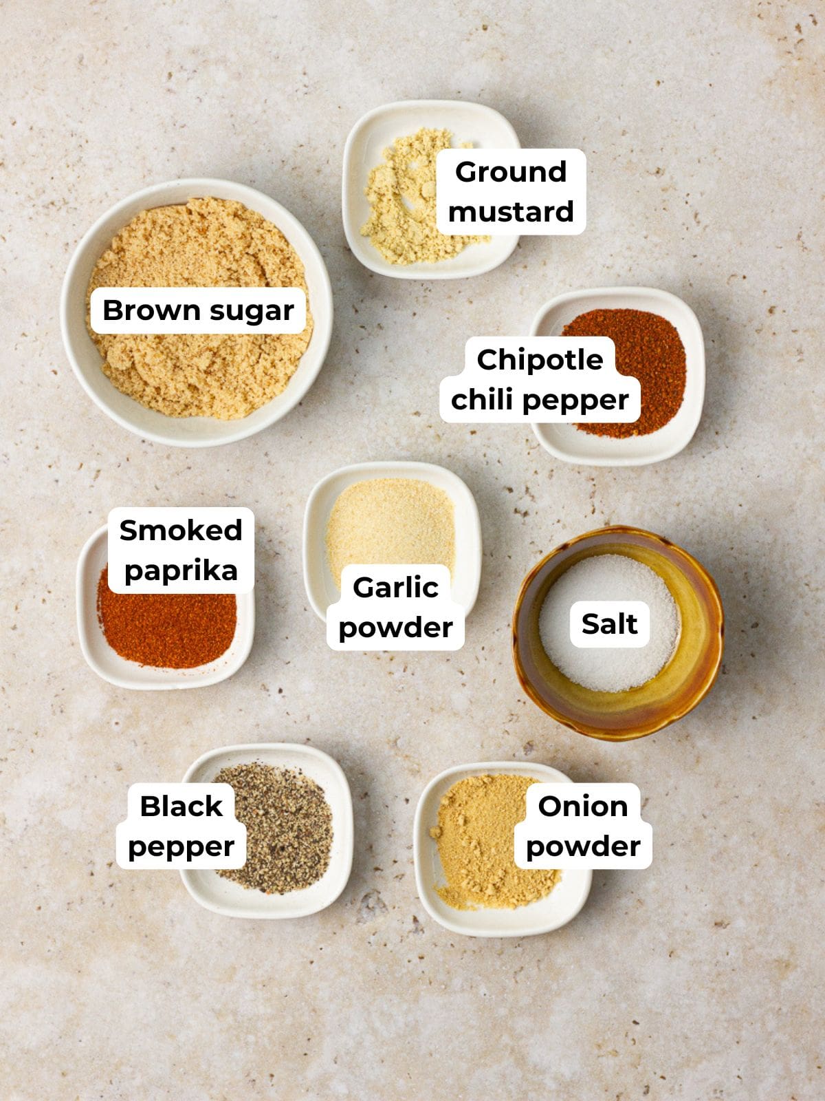A flat lay of eight small bowls showing labeled ingredients used in sweet and smoky rub.