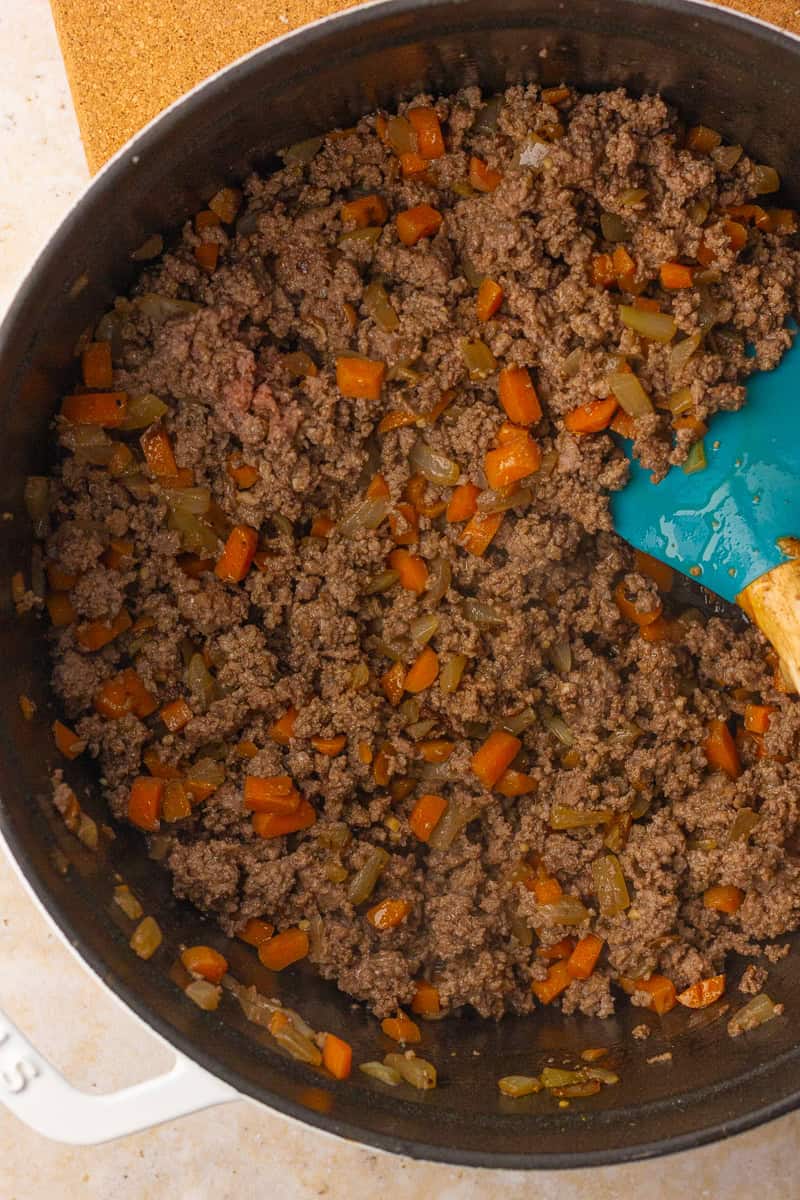Ground beef, carrots, and onions cooking in a Dutch oven for homemade Shepherd's pie.