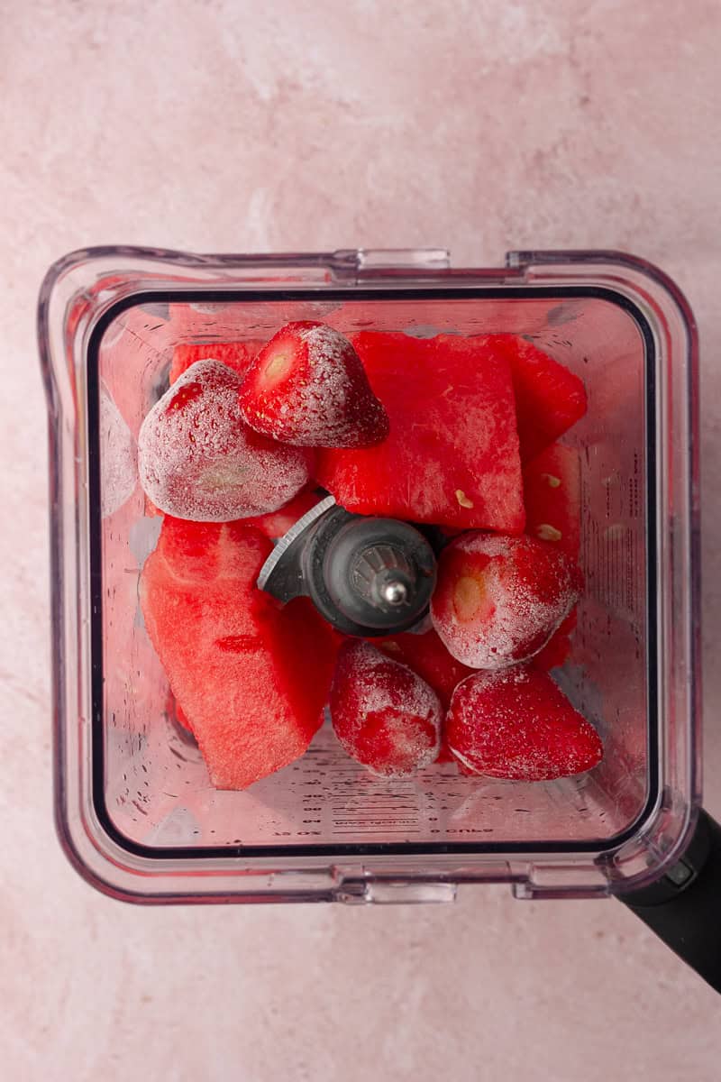 Frozen strawberries and fresh watermelon chunks in a blender, ready to be blended for margaritas.
