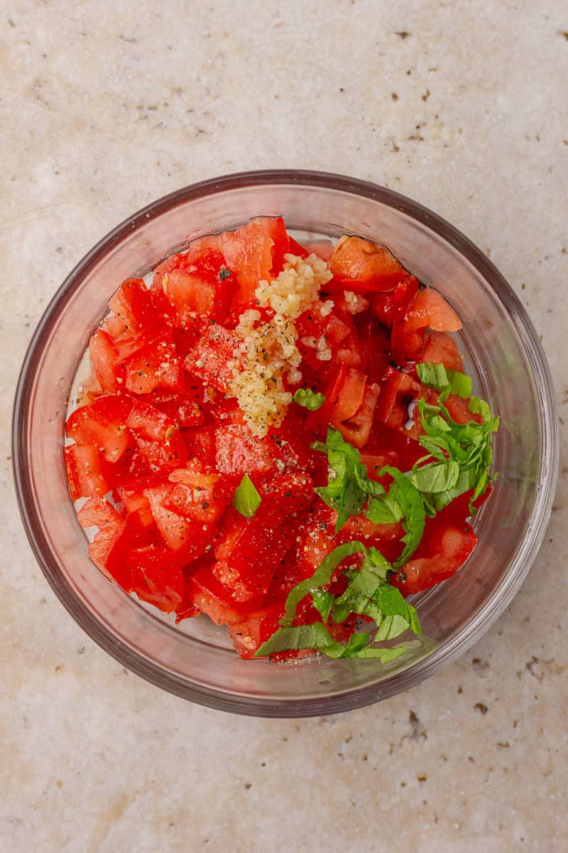 Fresh bruschetta topping with diced tomatoes, basil, and balsamic in a white bowl.