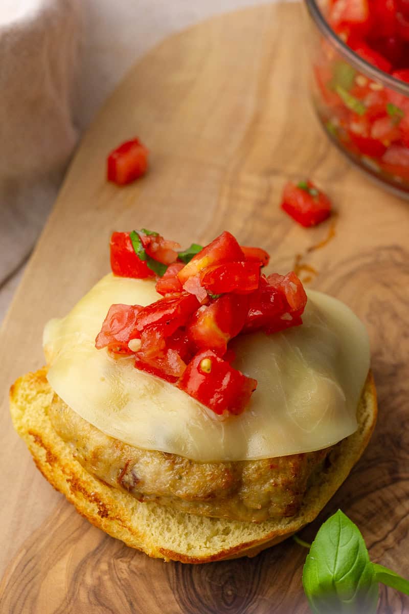 Bruschetta topping spooned over a cooked chicken patty on a bun.