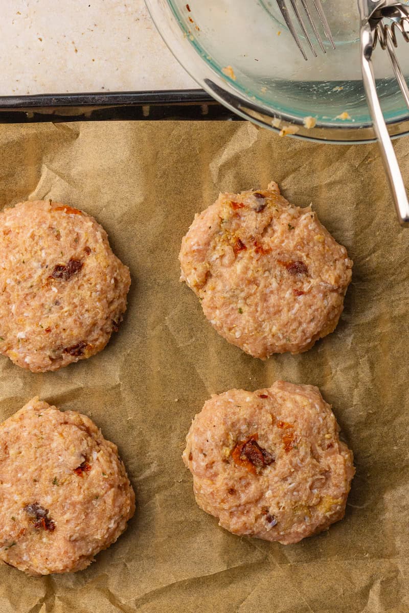 Raw ground chicken burger patties shaped and ready to cook in the air fryer basket.
