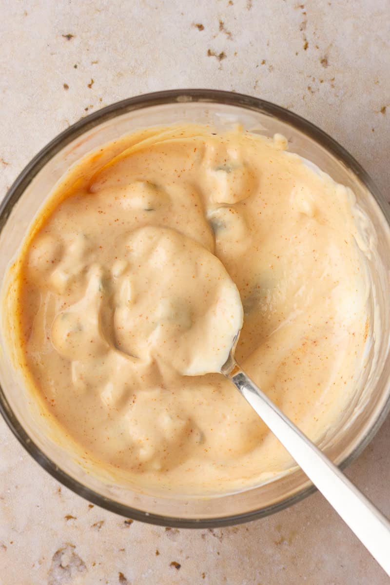 A bowl of creamy special sauce dressing with a spoon for serving.