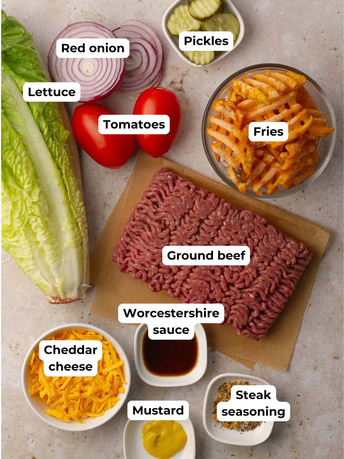 All burger bowl ingredients displayed including ground beef, waffle fries, lettuce, tomatoes, onion, pickles, cheddar, mustard, Worcestershire sauce, and steak seasoning.