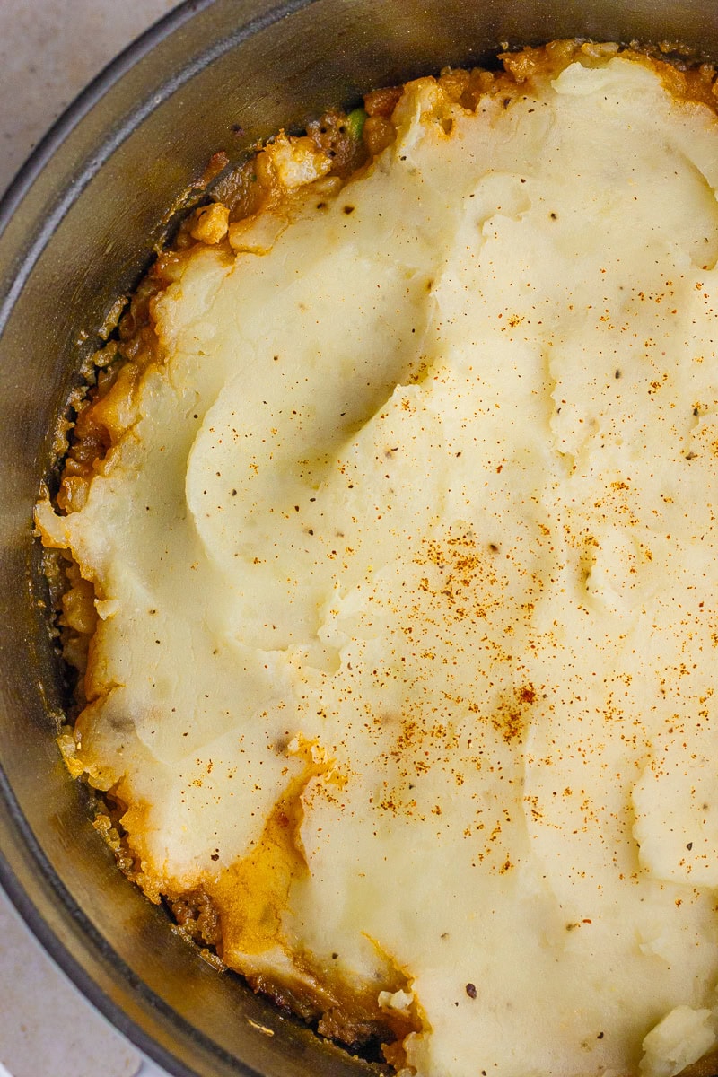 Close-up of golden-topped Dutch oven Shepherd's pie with beef and vegetable filling.