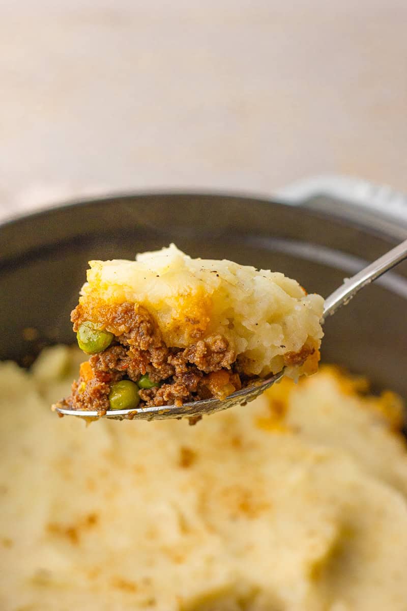 A spoonful of Dutch oven Shepherd's pie with fluffy mashed potatoes, beef, and vegetables.