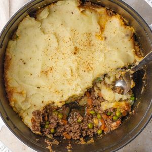 Overhead view of Dutch oven Shepherd's pie with a scoop removed, showing the filling.