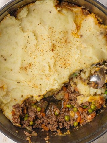 Overhead view of Dutch oven Shepherd’s pie with a scoop removed, showing the filling.