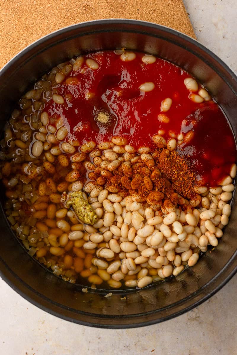 Navy beans, tomato sauce, BBQ sauce, broth, mustard, and spices are added before into pot.