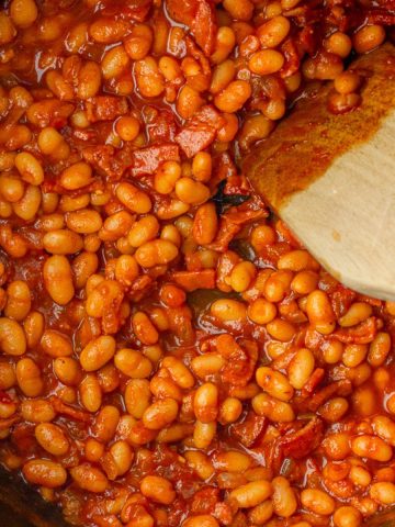 Overhead pot of Dutch oven low sodium baked beans with a wooden spoon ready to serve.