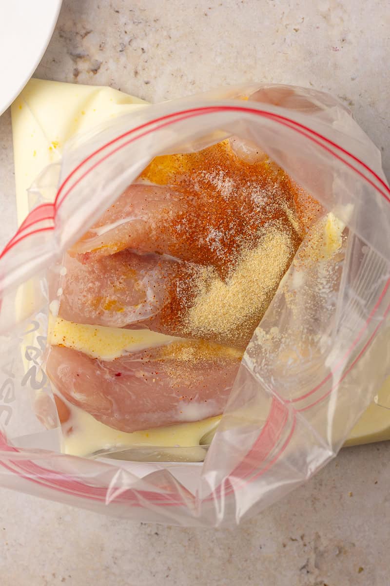 Chicken tenderloins marinating in buttermilk with paprika and garlic in a zip-top bag.