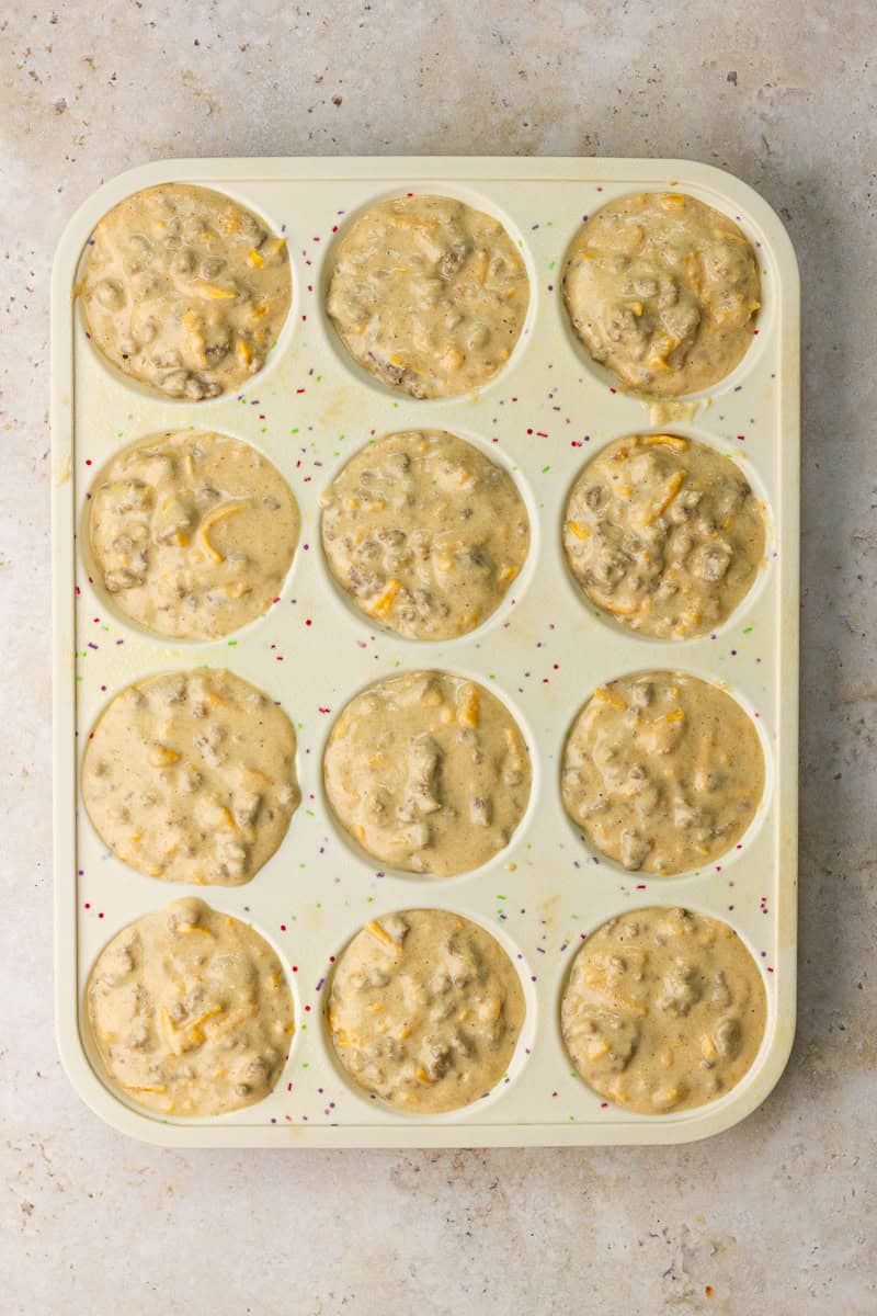 Muffin pan filled with sausage pancake batter ready to bake.