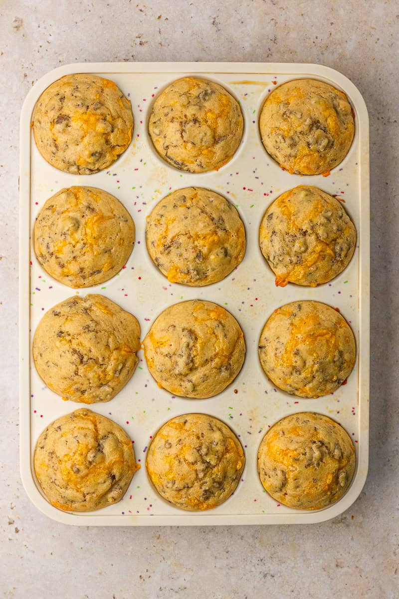 Freshly baked pancake sausage muffins with golden cheddar tops in the pan.