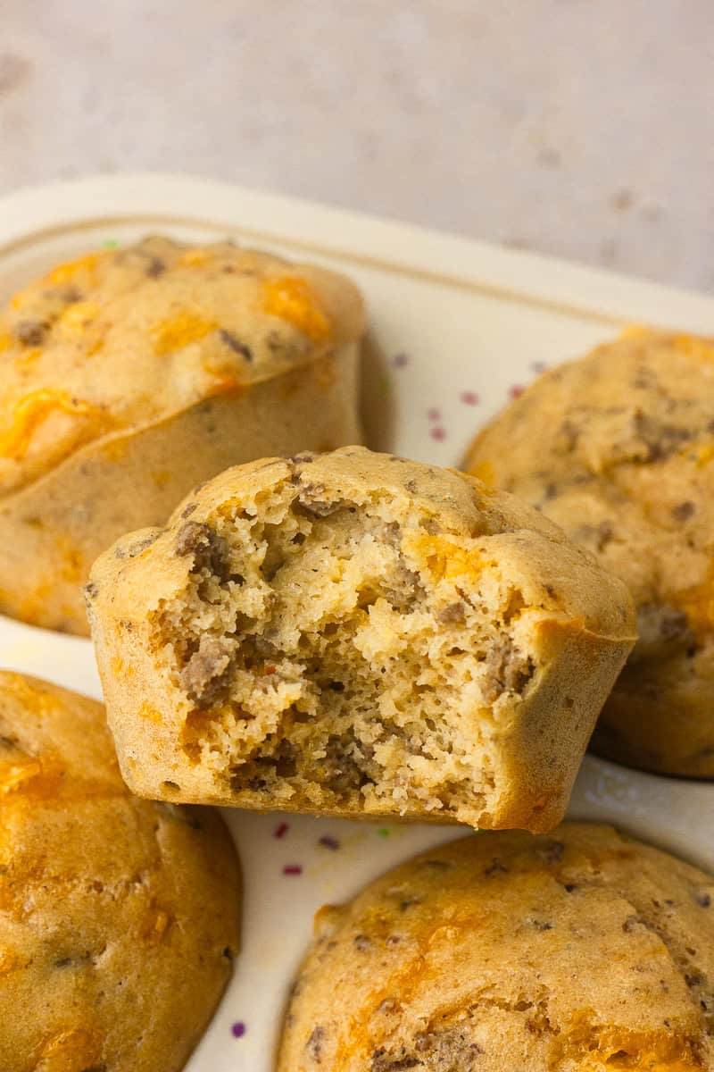 Pancake sausage muffin with a bite taken out showing tender crumb and sausage pieces.
