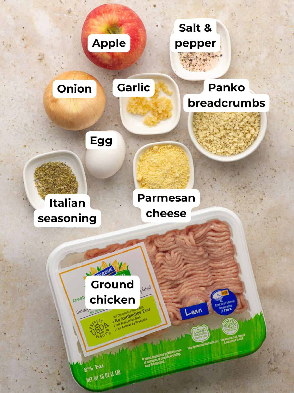 Ground chicken, grated apple, onion, egg, breadcrumbs, Parmesan, and seasonings arranged on a counter.